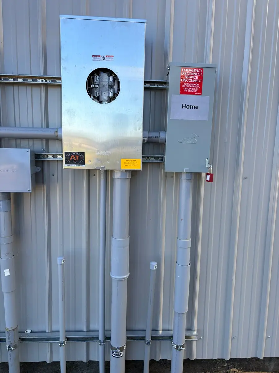 Close view of an electric meter beside a gray box labeled Home
