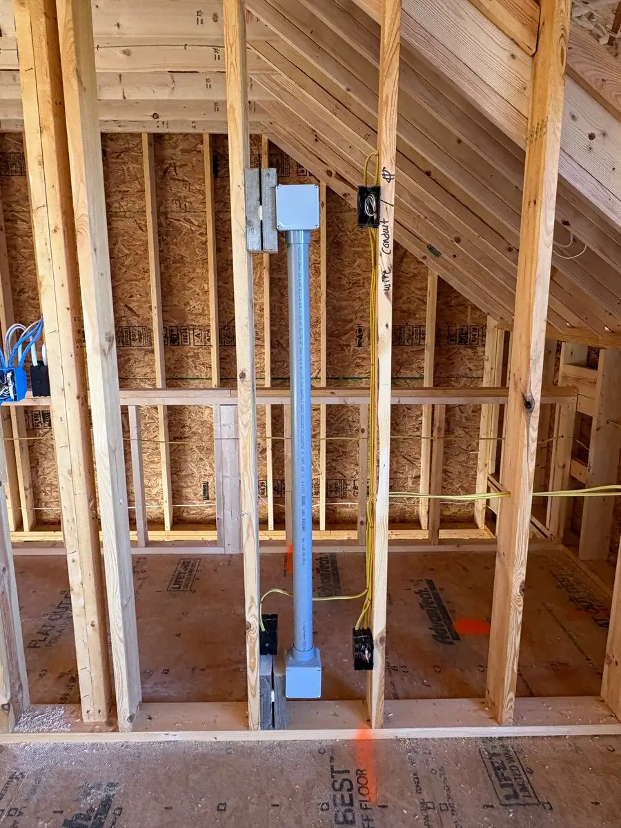Metal pipe running between two electrical boxes in unfinished upstairs framing